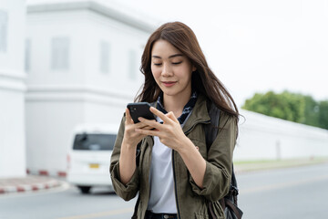 Asian attractive woman backpacker chatting on phone while walk in city. 