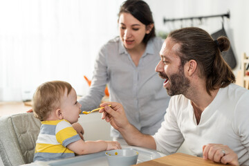 Obraz na płótnie Canvas Caucasian beautiful parents take care of baby boy toddler in kitchen.