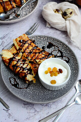 Vertical view of a plate with delicious pancakes with chocolate syrup on a gray background. Close-up