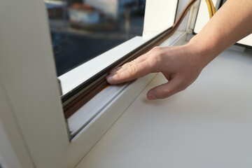 Construction worker putting sealing foam tape on window, closeup