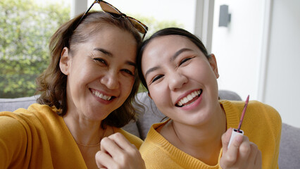 POV close-up face skin of mature elder mom and girl look at camera play fun game get dressed in asia mother day good life warm time. Cute teen people love enjoy social media app relax on sofa at home. © ChayTee