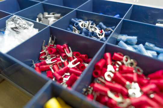 A set of colored crimp terminals for electrical wires. Crimping sleeves of different sizes. Plastic spare parts box for electrician. Toolbox. Selective focus
