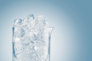 Glass ice bucket full of ice cubes in light blue tones.