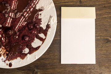 Notepad, cranberry cake, hot chocolate on the cake, powdered sugar.