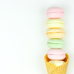 Yellow waffle cone with green, pink and yellow marshmallows looks like macaroons. Top view. Free space for text.