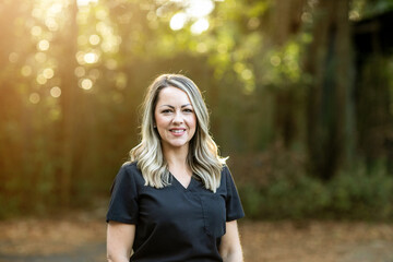A medical professional with black scrubs with long hair outside in a natural background with copy space
