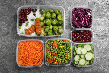 Set of plastic containers with fresh food on grey   table, flat lay