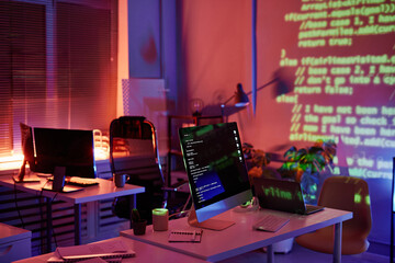 Abandoned openspace office with computer monitors on workplaces of diversity programmers or...