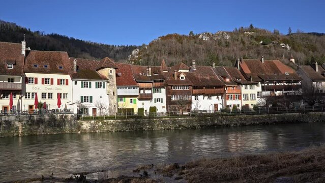 Medieval town Saint-Ursanne, Canton Jura, with beautiful facades of historic houses and stone bridge over river Doubs. Movie shot February 7th, 2022, Saint-Ursanne, Switzerland.