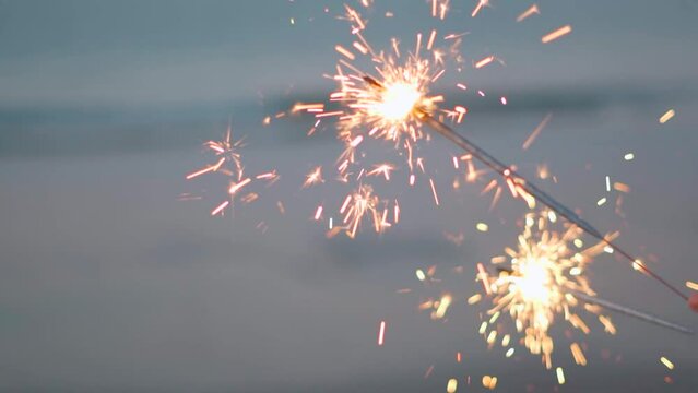 Close up of sparkler at evening on beach. Burning sparklers against the background of the bokeh of the evening seascape. Christmas tropical pattern. Happy New Year at the ocean.
