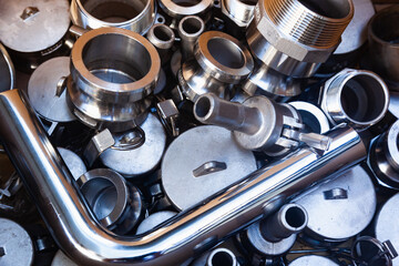 New pipe, bushings, couplings, threaded connections and stainless steel nipples. Pile of plumbing parts close-up.