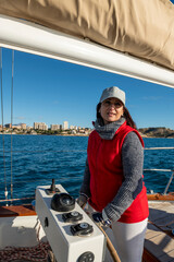 Adult Woman steering yacht on the bay of Alicante, Costa Blanca, Spain