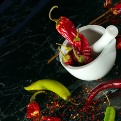 Chili pepper and pepper powder on a black .