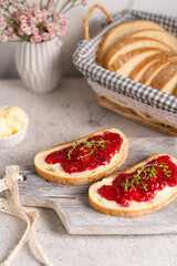 White bread slices with butter and raspberry jam on it, greens on wooden board, organic country sweet sandwich, homemade dessert. Copy space.