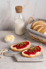 White bread slices with butter and raspberry jam on it, greens on wooden board, organic country sweet sandwich, homemade dessert. Copy space.