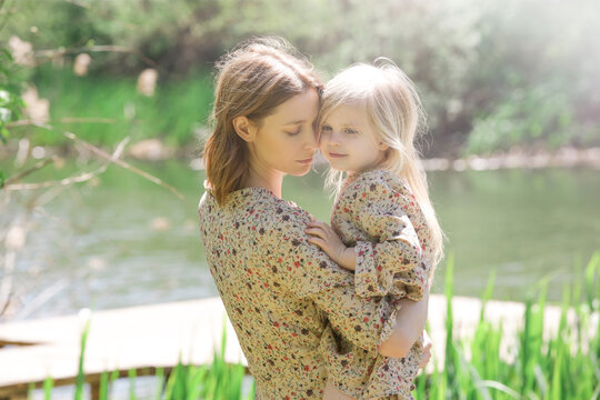 Mother and daughter in matching dress hugging during idyllic summer day. Carefree family time outdoor. Mother and child love.