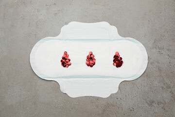 Menstrual pad with drops made of red sequins on grey background, top view © New Africa