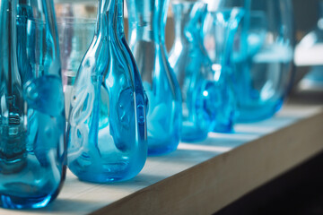 bottles of different sizes and shapes in blue on a shelf