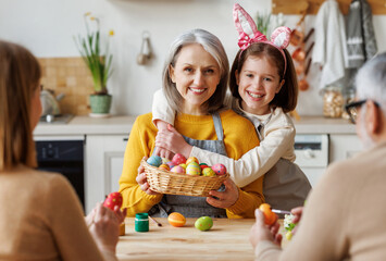 Happy family grandmother and little granddaughter holding wicker basket full of painted boiled eggs