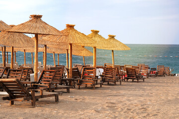 Straw umbrellas on tropical idyllic resort. Blue sea and sky with soft yellow sunlight.