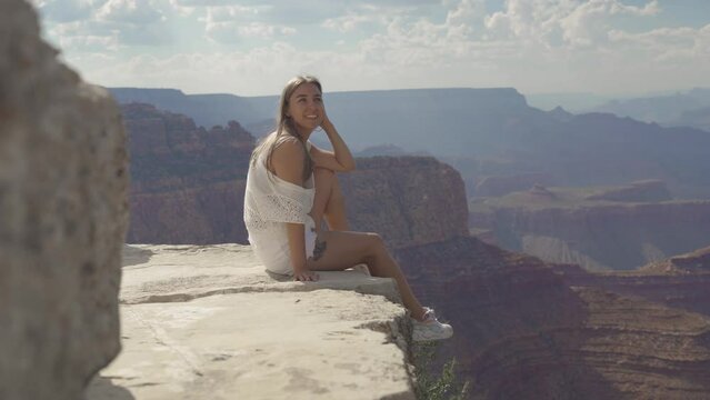 A young woman looking to Horseshoe Bend and Colorado river from the edge of 1000ft canyon in Glen Canyon National Recreation Area, Arizona, USA