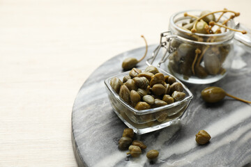 Delicious pickled capers on white wooden table, space for text