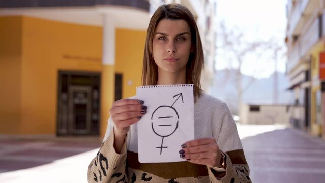 Medium shot of a young woman holds a paper with a gender equality symbol in slow motion