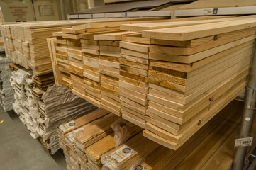A stack of boards in a hardware store. Wooden products for construction and repair. Assortment of wooden sticks. Construction materials in warehouse. Selective focus