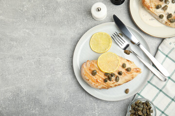 Delicious chicken fillet with capers and lemon served on light grey table, flat lay. Space for text