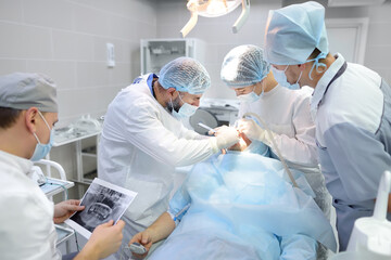 Surgeons and nurse during a dental operation. Medical team performing surgical dentistry operation....