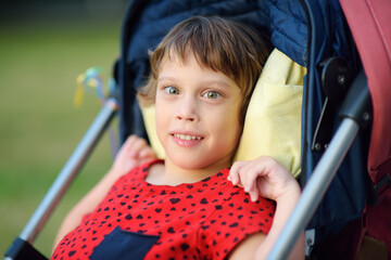 Portrait of a little disabled girl in a wheelchair. Child cerebral palsy. Treatment and rehabilitation of CP. Inclusion. Family with disabled kid. Handicapped baby