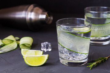 cocktail with lime.Cucumber water with lime. glass of Homemade flavoured lemonade with rosemary and shaker on the black table. detox water. cold summer lemonade with copy space.