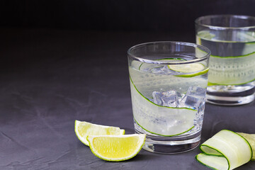 glass of water with lime.Cucumber water with lime and rosemary. glass of Homemade flavoured lemonade on the black table. detox water. cold summer lemonade with copy space.