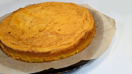 Delicious curd-pumpkin casserole on parchment with a black square plate on a white background