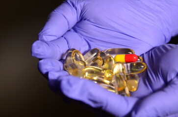 Choice of pills, red or blue. Hands in lilac medical mittens hold multi-colored pills. Medicines...