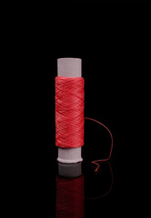 A skein of thread, a spool of thread for sewing, on a black background isolated with reflection