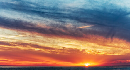 Obraz na płótnie Canvas Dramatic sunset sky with clouds and sun by the horizon. Soft focus.