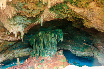 View of beautiful natural pool of crystal clear water formed in a rocky cave with stalagmites and stalagmites. Kuza cave in Zanzibar, Tanzania
