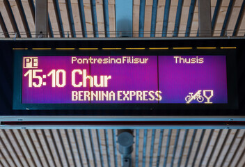 Poschiavo, Switzerland - January 19, 2022: Digital billboard on the railway platform announcing the departure schedule of Bernina Express train from Poschiavo in direction of Chur, Switzerland