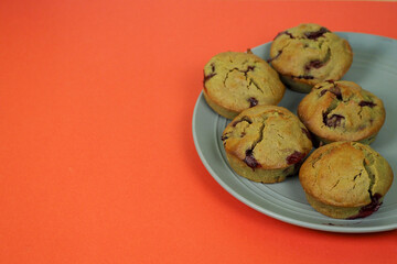 five muffins made of rice flour, yogurt, cherries and pumpkin oil lie on a white plate on a red background, side view. gluten-free homemade cakes