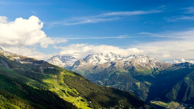 Scenic view of beautiful landscape in Swiss Alps. Fresh green meadows and snow-capped mountain tops in the background in springtime, Switzerland.