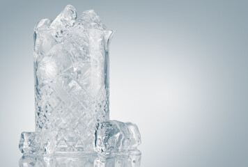 Glass tray full of ice cubes on light background on a reflective surface. Ice bucket with copy space.