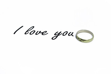 Inscription I love you on a white background. Behind the text a gold ring with stones. Valentine's Day.
