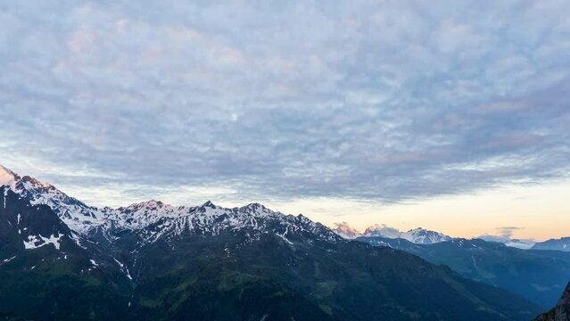 Scenic view of beautiful landscape in Swiss Alps. Fresh green meadows and snow-capped mountain tops in the background in springtime, Switzerland.