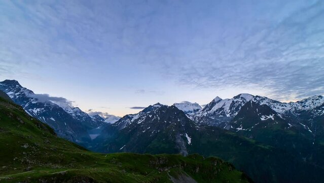 Scenic view of beautiful landscape in Swiss Alps. Fresh green meadows and snow-capped mountain tops in the background in springtime, Switzerland.