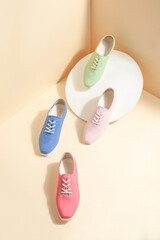 Women stylish multi colored sneakers isolated on beige background; space for text; perspective view