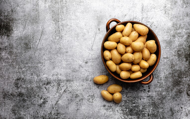 Raw small potatoes in a cast iron skillet on a beton background.