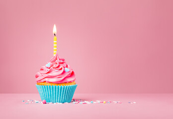 Pink Birthday Cupcake with yellow Candle and Blue Heart Sprinkles - 485670721