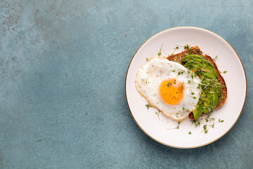 Keto breakfast fried egg, avocado and bread in a white plate. Keto diet concept.