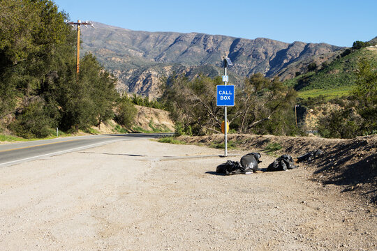 Call Box On The Shoulder Of A Highway Where Trash Bags Have Been Thrown